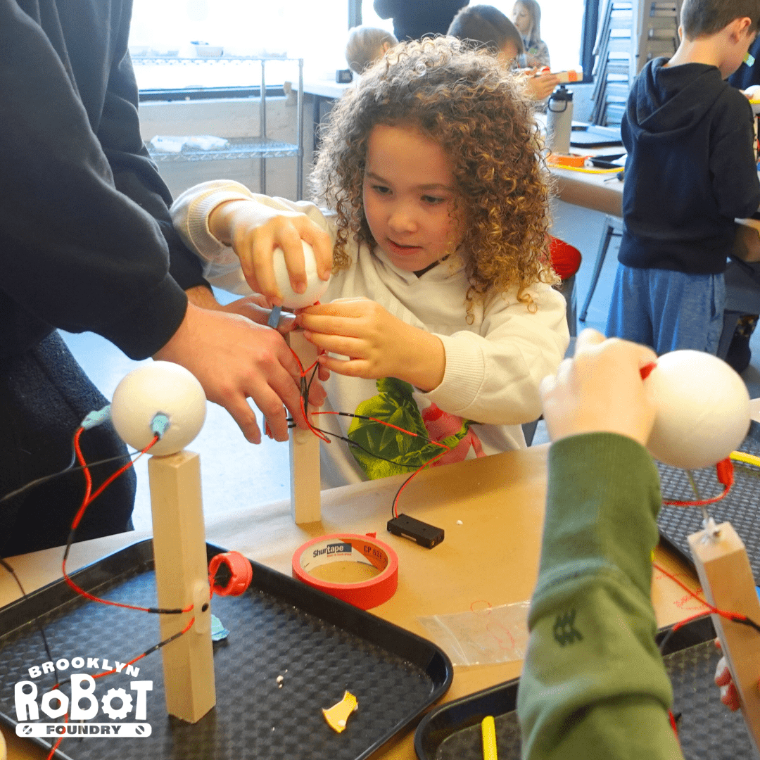 Photograph of child working on adding a styrofoam ball to their robot.