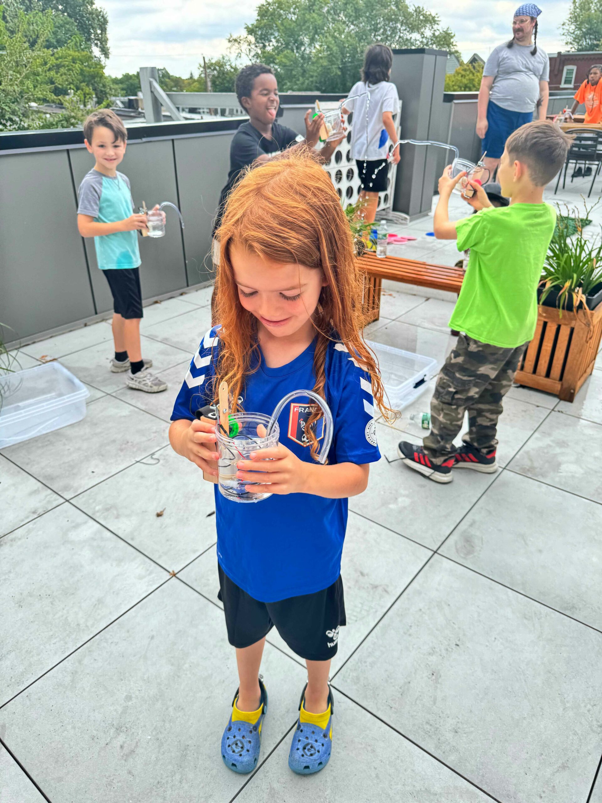 Photo of a bunch of children outside playing with the water robots they built