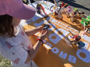 Child holding a minibot in front of a robotics table with several other robots displayed
