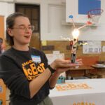 Photo of Brooklyn Robot Foundry teacher holding up a lit-up robot at an event