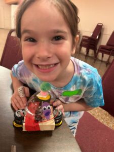 Photo of child holding up robot and smiling for the camera