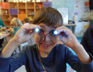 Photo of child holding up 2 LED's in front of their eyes