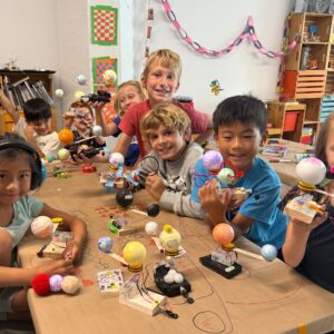 Photo of group of children around a table holding up their finished robots